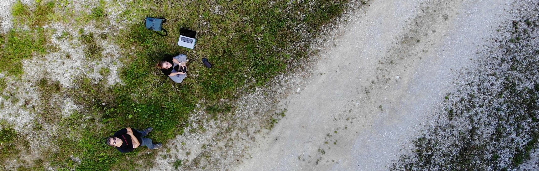 Künstler Oliver Ressler und Drohnenpilotin Verena Tscherner auf einer Wiese von oben fotografiert