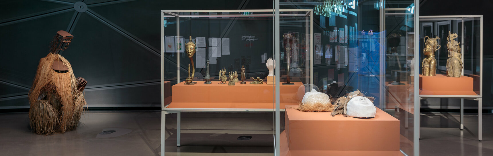 Ausstellungsansicht im Kunsthaus Graz. Mehrere Vitrinen mit den Bronzeskulpturen und Masken vom Künstler Samson Ogiamien sind groß im Bild zu sehen.