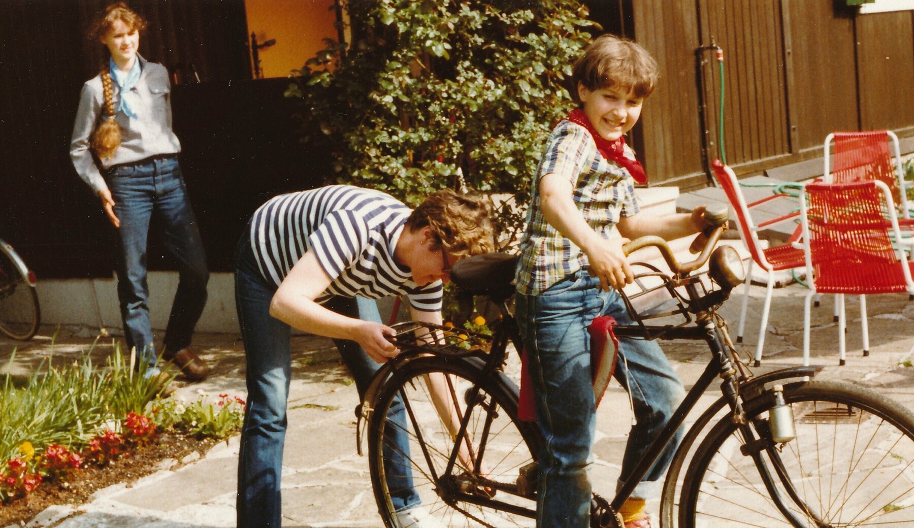 Farbfotografie der Tochter und Enkelinnen von Christian Willomitzer mit dem noch schwarz lackierten Fahrrad im Garten, Sommer 1982