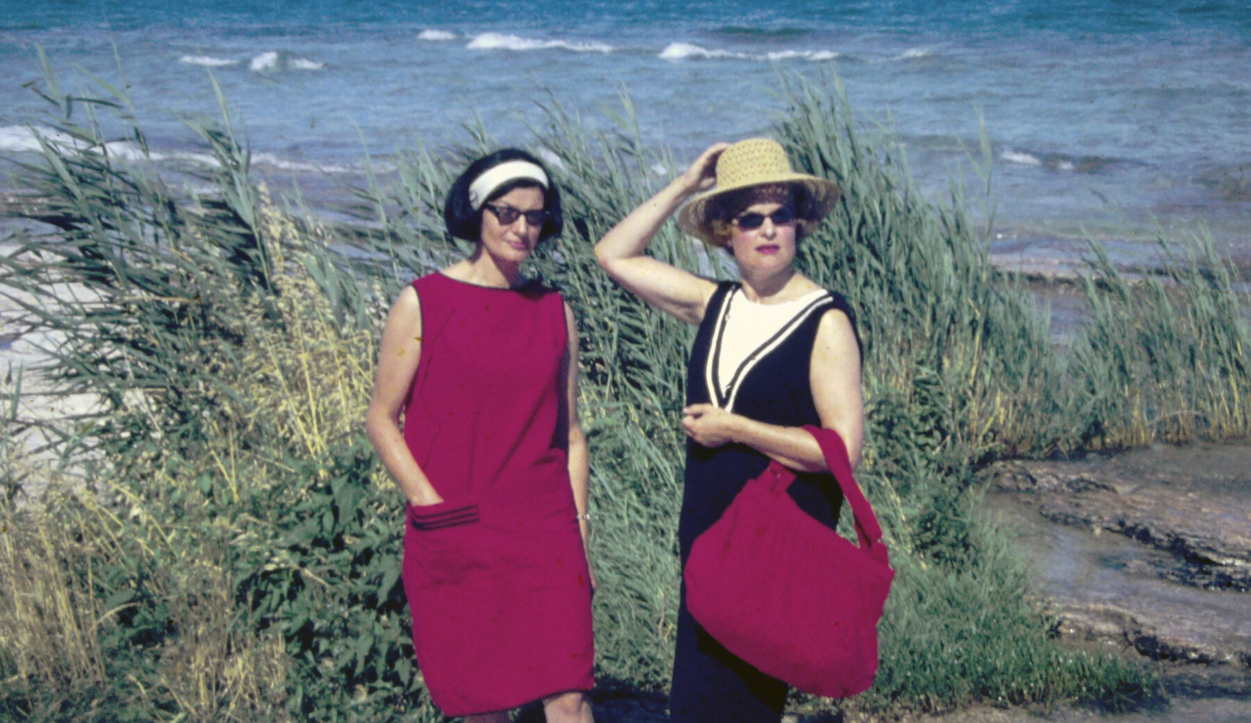Ein Urlaubsdia mit zwei eleganten Grazer Damen an der Adriaküste mit roter Badetasche und rotem Kleid.