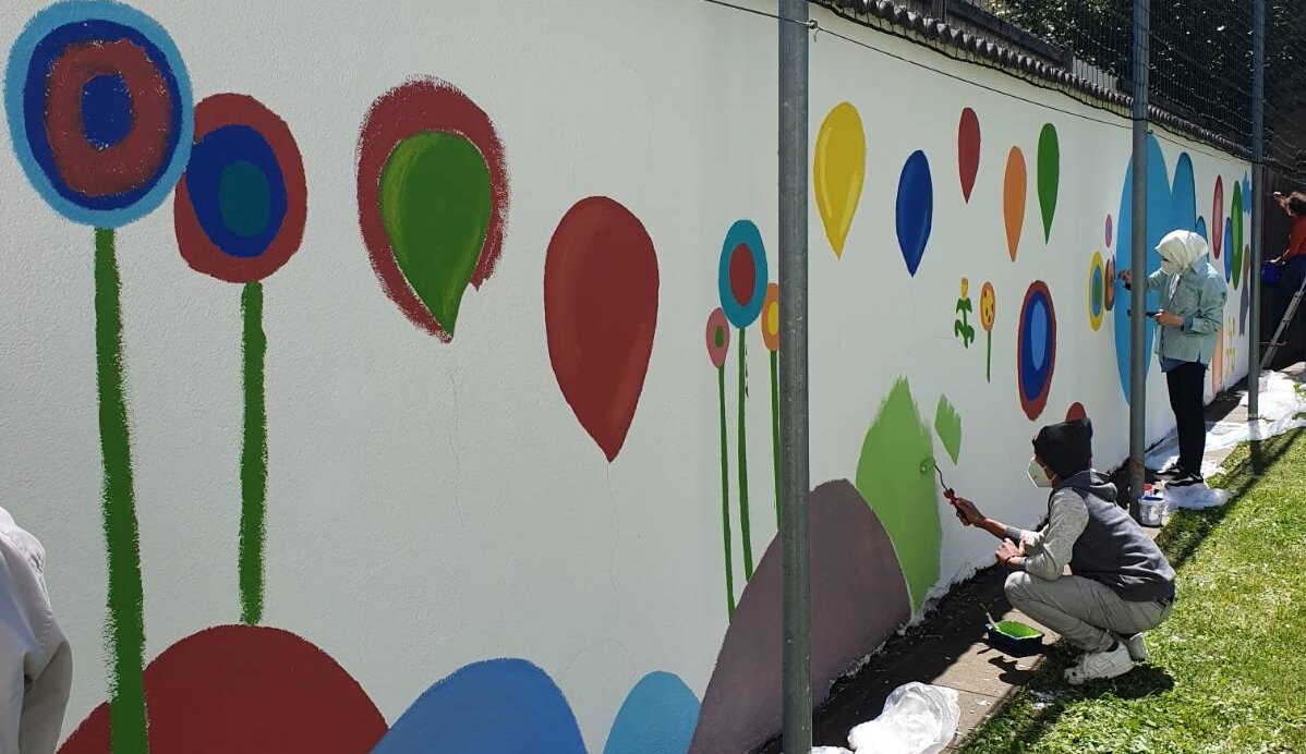Ansicht des Schulhofs in der Mittelschule St Anrä. Schülerinnen und die Künstlerinnen malen die Hofmauer neu aus