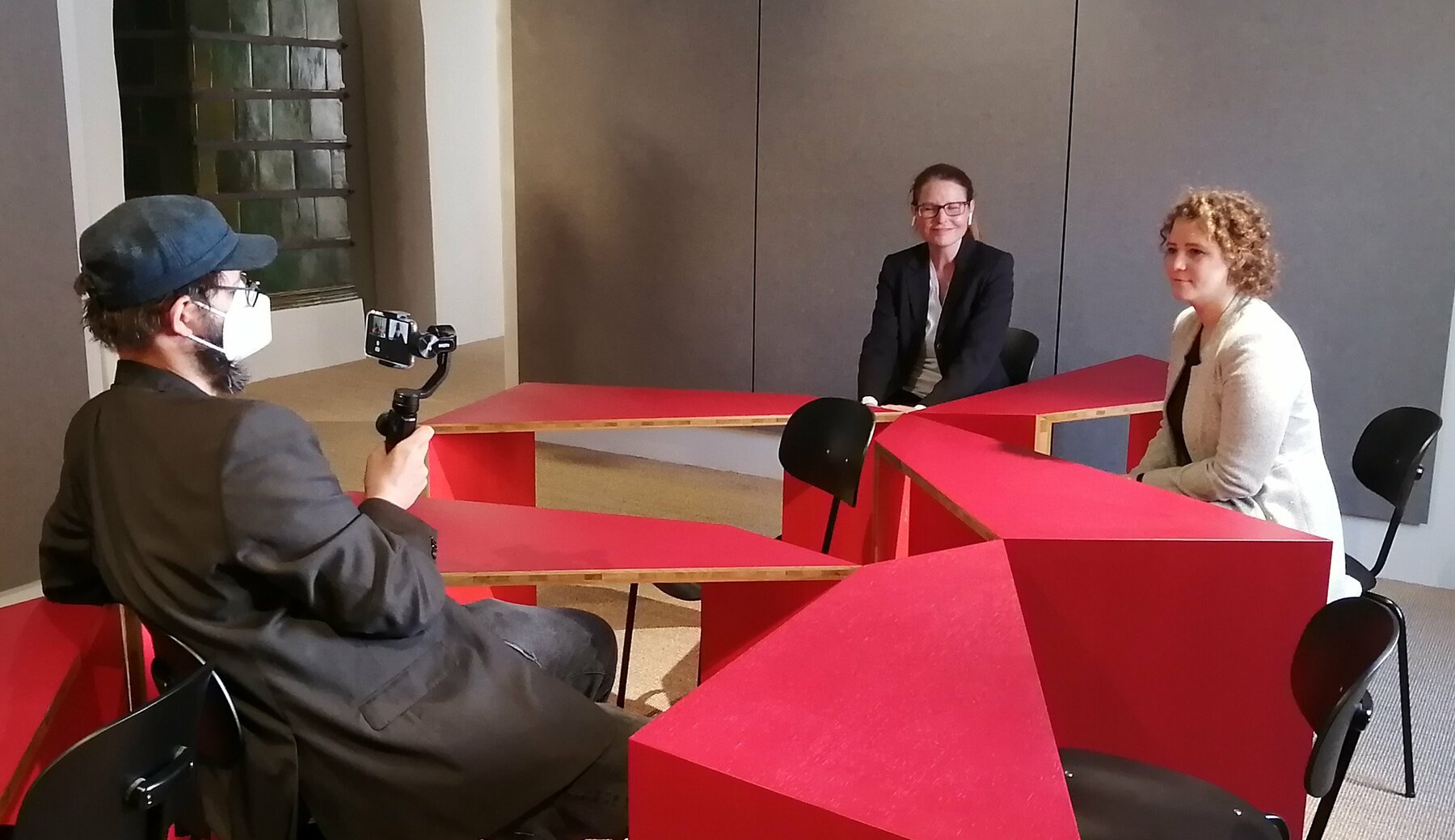 Das sogenannte Mitsprechzimmer im Volkskundemuseum: Um rote Tischelemente sitzen Kolleginnen von der Vermittlung und bereiten eine Veranstaltung vor