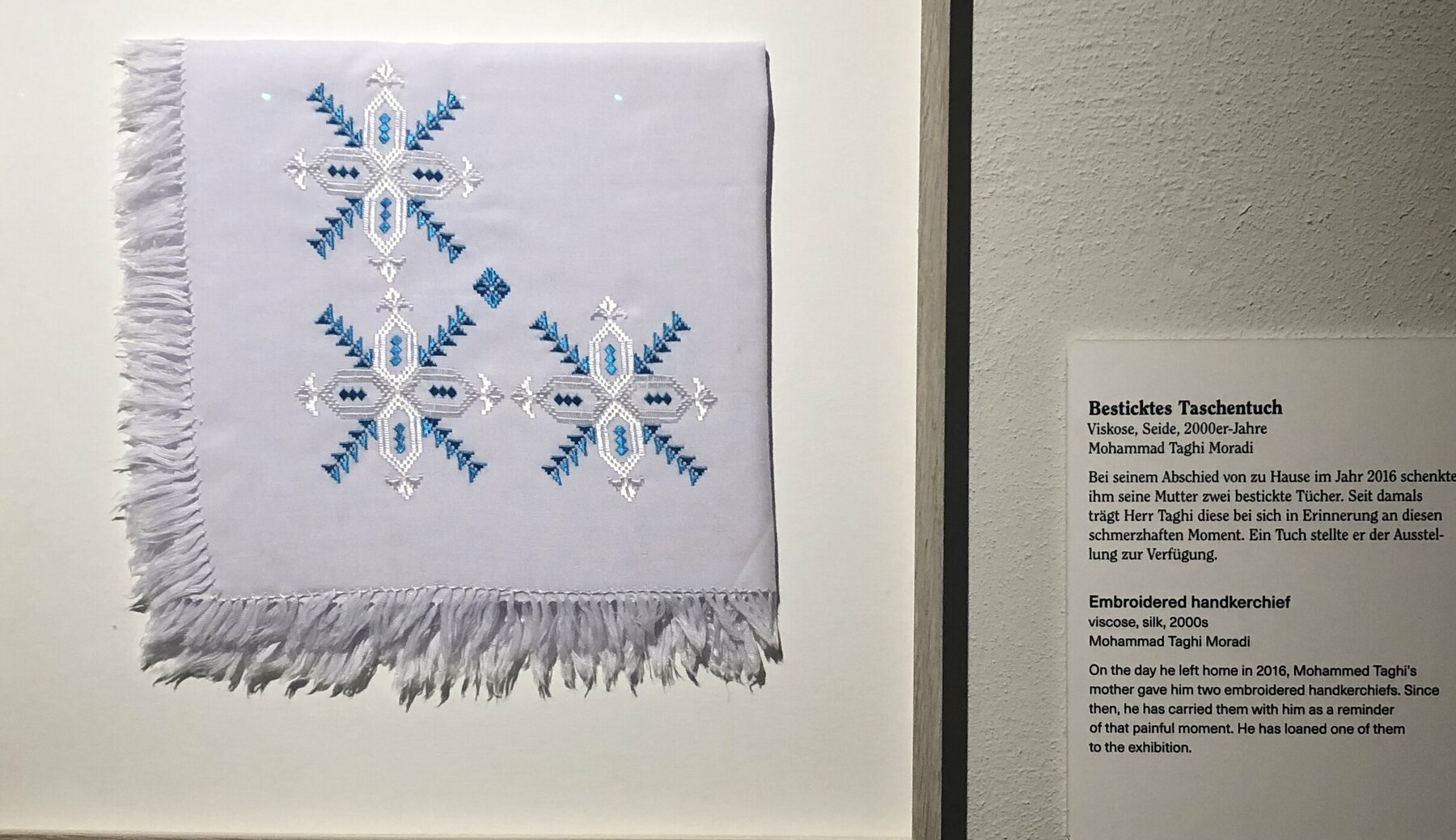 Besticktes Taschentuch in Rahmen an der Wand in der Ausstellung. Ein Geschenk der Mutter von Mohammad Taghi Moradi bei seinem Abschied 2016 aus Afghanistan. 