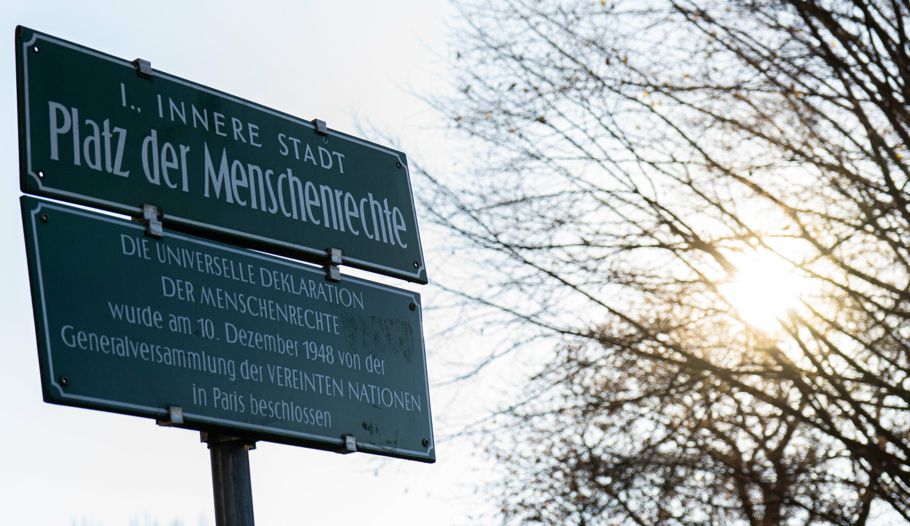 Straßenschild in Graz mit der Aufschrift: "Platz der Menschenrechte. Die universelle Deklaration der Menschenrechte wurde am 10. Dezember 1948 von der Generalversammlung der Vereinten Nationen in Paris beschlossen."