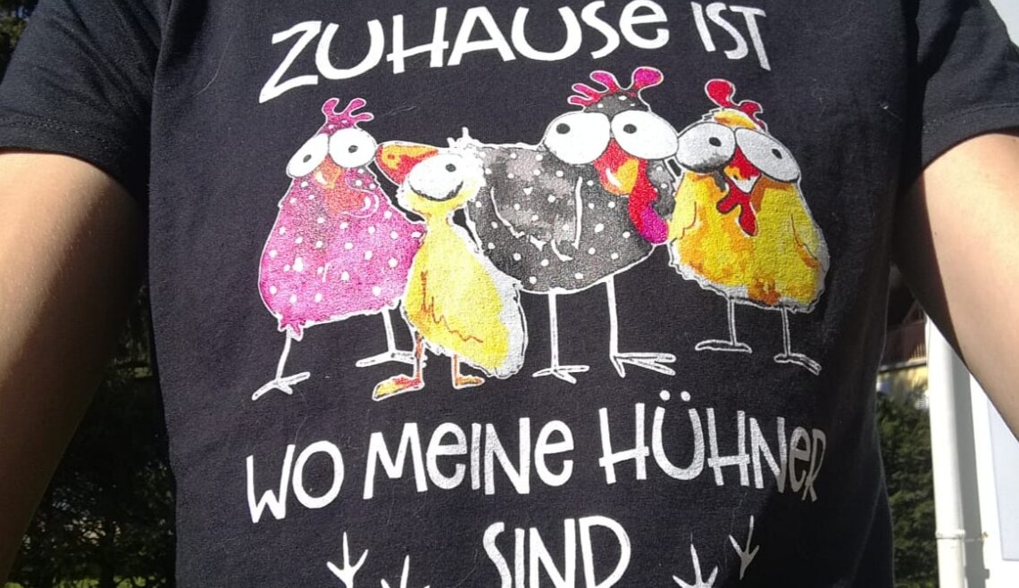 Schwarzes T-Shirt mit 4 bunten Hühnern und Aufschrift "Zuhause ist, wo meine Hühner sind"