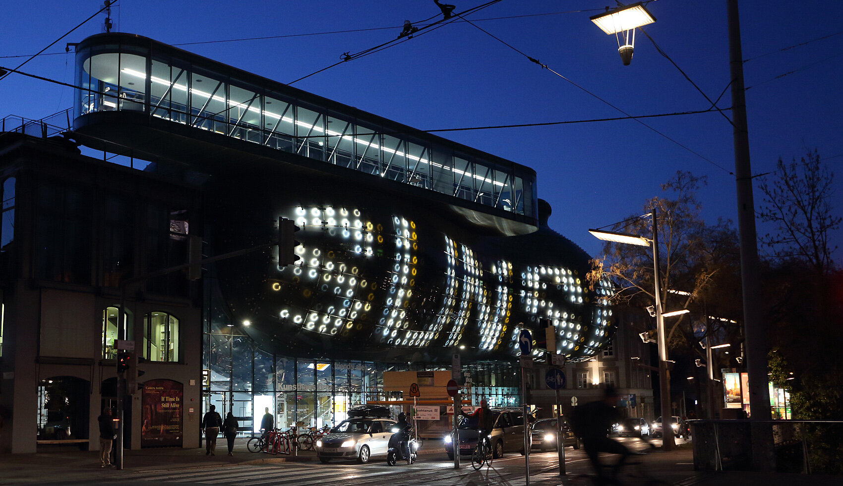 Eine Außenaufnahme des Kunsthauses Graz, die BIX Medienfassade leuchtet und zeigt den Schriftzug Sunscriber