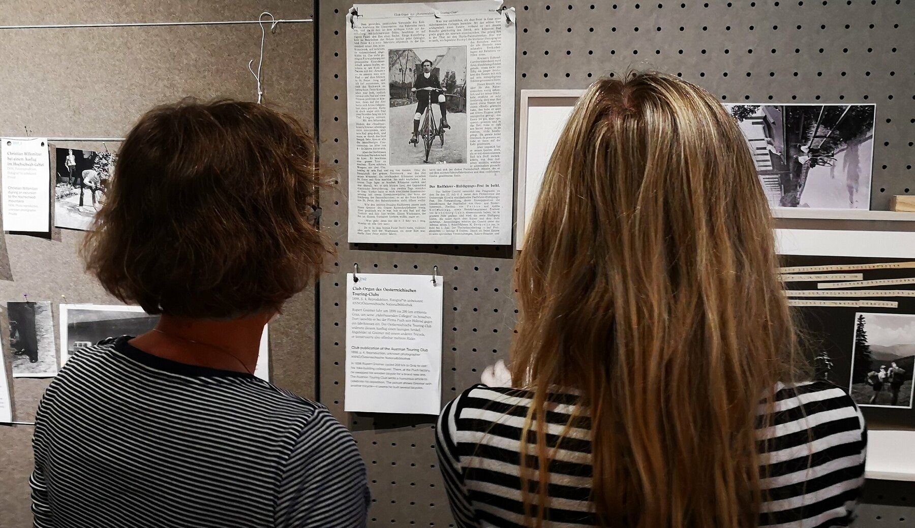 Zwei Kolleginnen prüfen vom Betrachter abgewandt die Anordnung von Ausstellungsexponaten