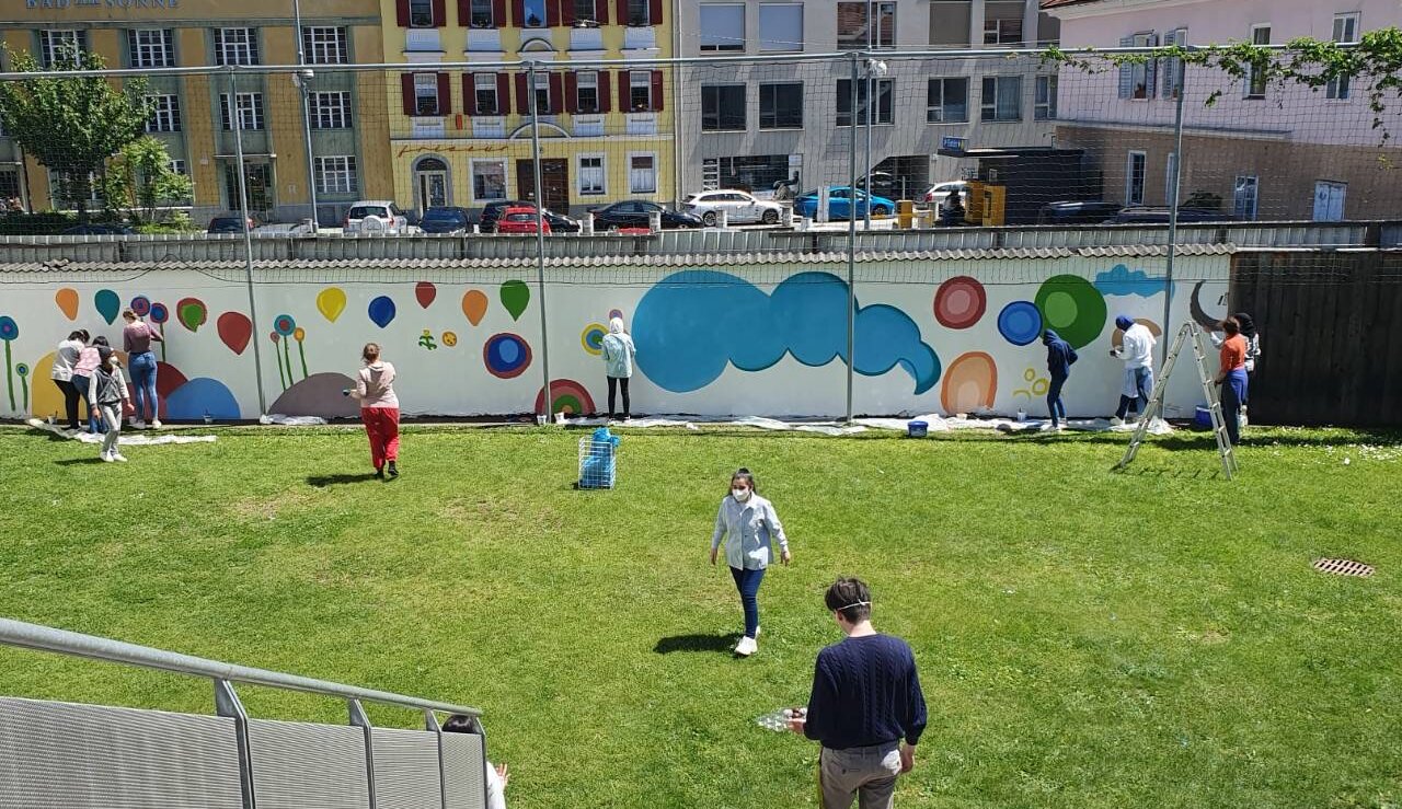 Ansicht des Schulhofs der Mittelschule St- Andrä in Graz. Gemeinsam mit den Künstlerinnen malen die Schüler und Schülerinnen die Hofmauer neu aus